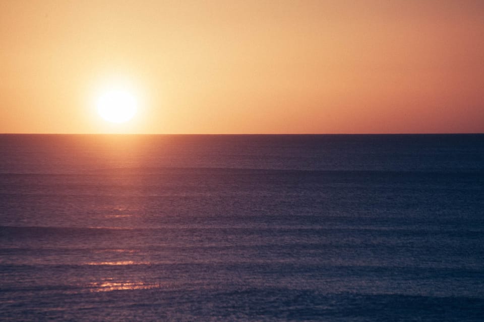 Sun rising over the sea on wainui beach gisborne - the first land in the world to see the sun rise